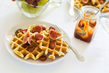 Healthy breakfast: Belgian waffles with figs, grapes and caramel on white table cloth. Selective focus