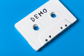 empty white audio cassette with an inscription "demo" on a blue background