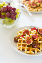 Healthy breakfast: Belgian waffles with figs, grapes and caramel on white table cloth. Selective focus