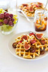 Healthy breakfast: Belgian waffles with figs, grapes and caramel on white table cloth. Selective focus