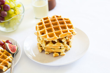 Healthy breakfast: Belgian waffles with figs, grapes and caramel on white table cloth. Selective focus