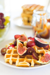 Healthy breakfast: Belgian waffles with figs, grapes and caramel on white table cloth. Selective focus