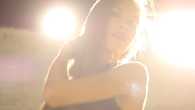 Young sexy woman 25-30 with very long flowing hair dances go-go outdoor at night.