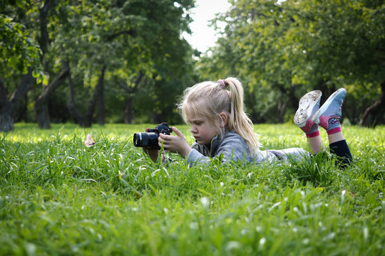 Little girl photographer. Child photographing a butterfly