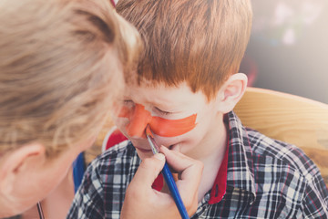 Child boy face painting, making tiger eyes process