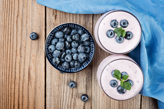 Smoothie or milkshake with  blueberries  in a glasses on rustic wooden  table, top view