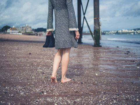 Woman walking on beach with shoes in hand