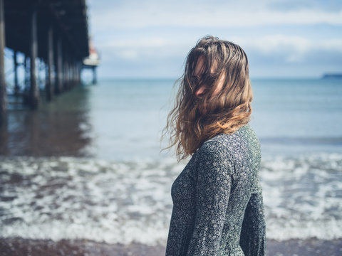 Young woman standing by a pier on the beach