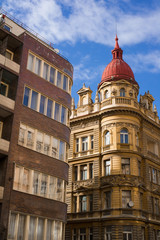 Contrast between old historical townhouse with a lot of decoration and ornaments and modern residential building. Heterogeneity, diversity and variedness of architecture