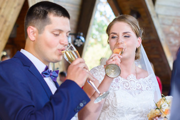Young bride and groom at the wedding ceremony under the arch, a restaurant in wooden country style. Wedding in the countryside in village style