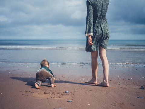Mother on beach with baby crawling into sea