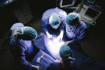 Team of surgeons performing surgery in operation theater - obrazy, fototapety, plakaty