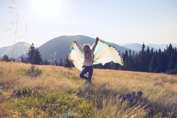 Joyful teenage girl runs along the alpine meadow