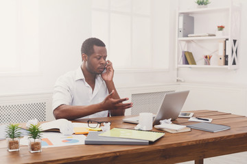 Fototapeta premium Young black businessman call mobile phone in modern white office