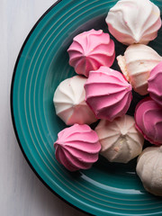Fototapeta premium Pastel color pink and white meringue on green background