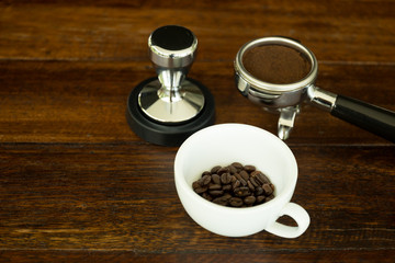 Concept and idea cup with coffee beans and and coffee ground and tamper