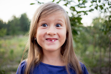 Young little girl without a front tooth in the countryside