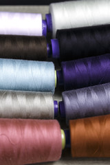 Group of bobbins of thread of various colors on a wooden table
