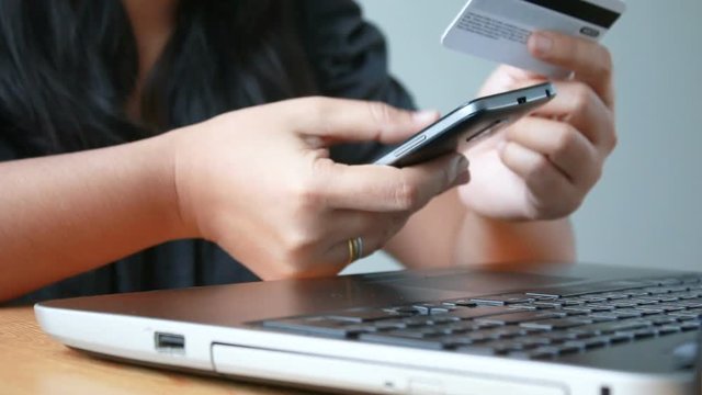 Close up shot hands of woman using laptop computer and smart phone with holding credit card metaphor concept for online shopping internet application and e commerce concept

