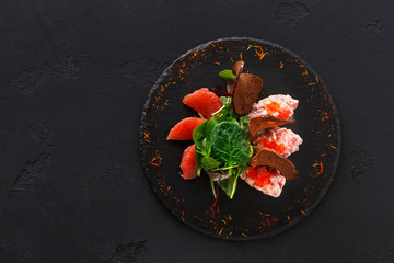 Gourmet seafood snack on black plate top view