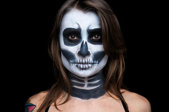 close up portrait of woman with Halloween skull make up over black background.