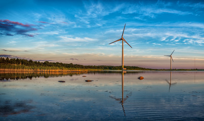 Two windmills at sunset making work. Beautiful seascape.