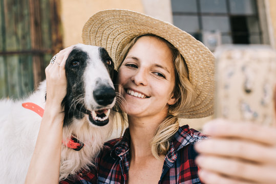 Young woman taking self portrait with her dog