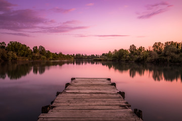 Pier on a lake at sunset in Tuscany