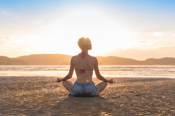 Fototapeta na wymiar Young Girl Sitting Lotus Pose On Beach At Sunset, Beautiful Woman Practicing Yoga Summer Vacation Meditation Seaside Sea Ocean Holiday Travel