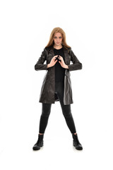 full length portrait of girl wearing black clothes with long leather jacket. standing pose on white background.