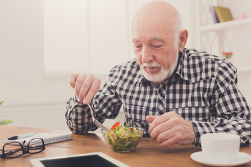 Senior man eating fresh salad copy space
