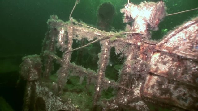Scuba diver near rusty wreckage shipwreck on beach of White Sea Russia. Unique history place for tourism.