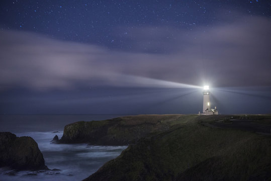 Scenic view of Yaquina Head Lighthouse on shore against star field