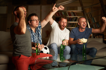 Four friends watching football game on television