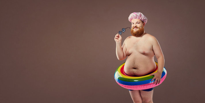 Funny fat bearded man in a swimsuit in for swimming inflatable ring.