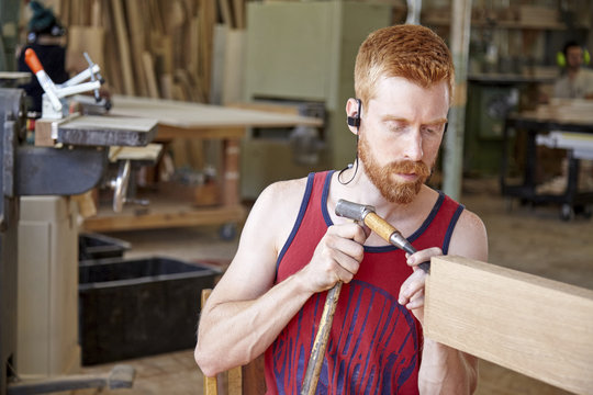 Carpenter wearing earphones while working in workshop