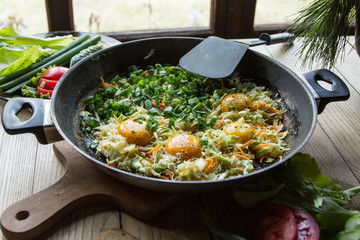 Fried eggs with vegetables in a pan