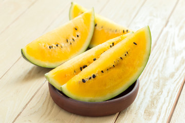 Fototapeta na wymiar Yellow watermelon sliced on wooden background