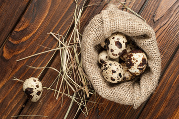 top view on quail eggs in burlap sack over old wooden background