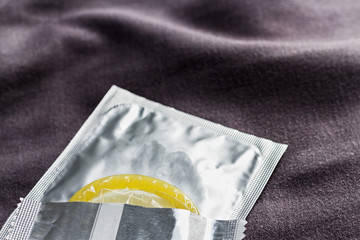 condoms and one open pack put on the brown cloth background.