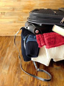 Suitcase full of clothes, book, camera and wallet for a trip. Travel concept