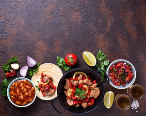 Concept of Mexican food.  Salsa, tortilla, beans, fajitas and te