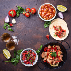 Concept of Mexican food.  Salsa, tortilla, beans, fajitas and te