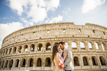 Fototapeta na wymiar Happy couple hugging in front of Colosseum in Rome, Italy
