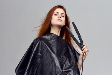 A woman holds a forceps to straighten her hair