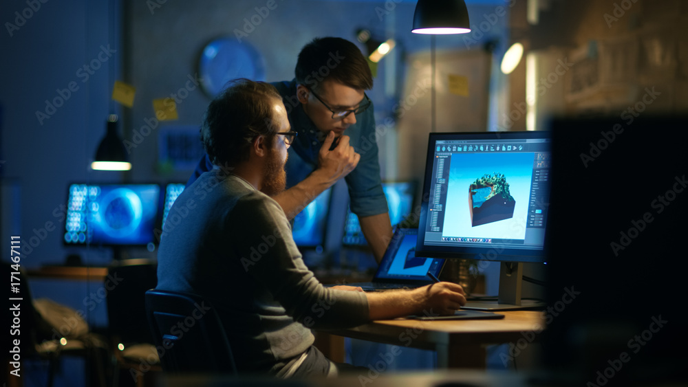 Poster two male game developers discuss game level drawing, one uses graphic tablet. they work late at nigh