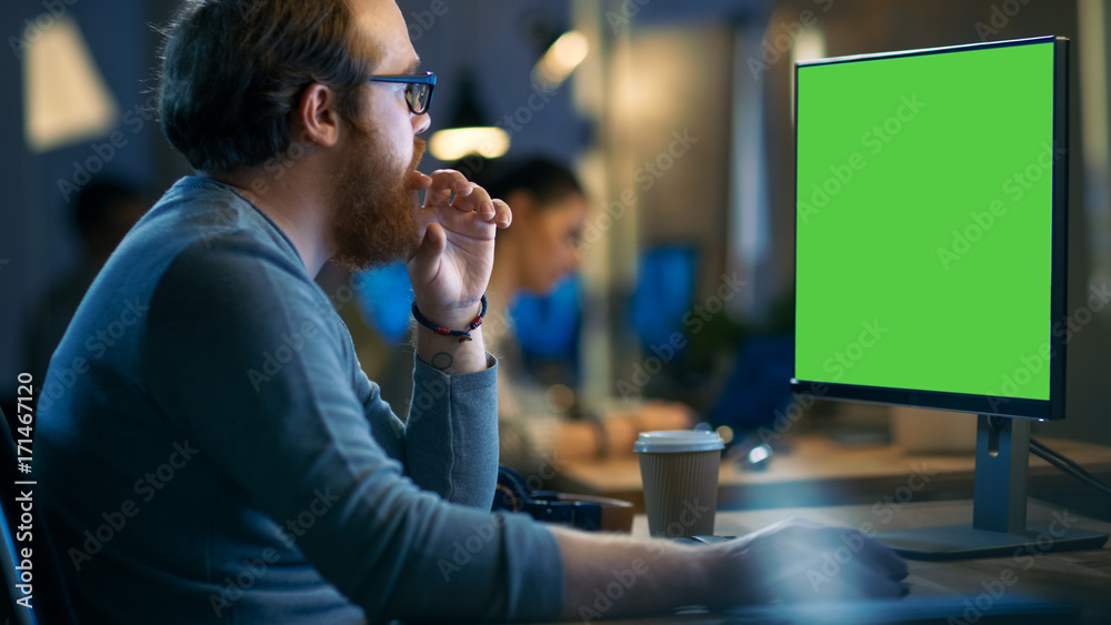 Poster creative bearded man works on a personal computer with isolated mock-up green screen. his office spa