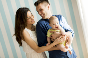 Portrait of mother and  father with cute little baby girl daughter in room