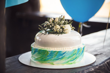 Birthday cake decorated by flowers on wood background