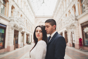 Beautiful wedding couple, bride, groom kissing and hugging against the background of old building